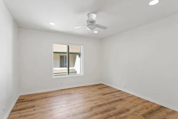an empty room with wooden floor chandelier fan and windows