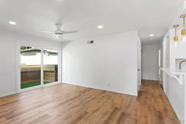 a view of empty room with wooden floor and fan