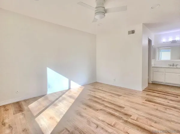 a view of a bedroom with wooden floor and a kitchen