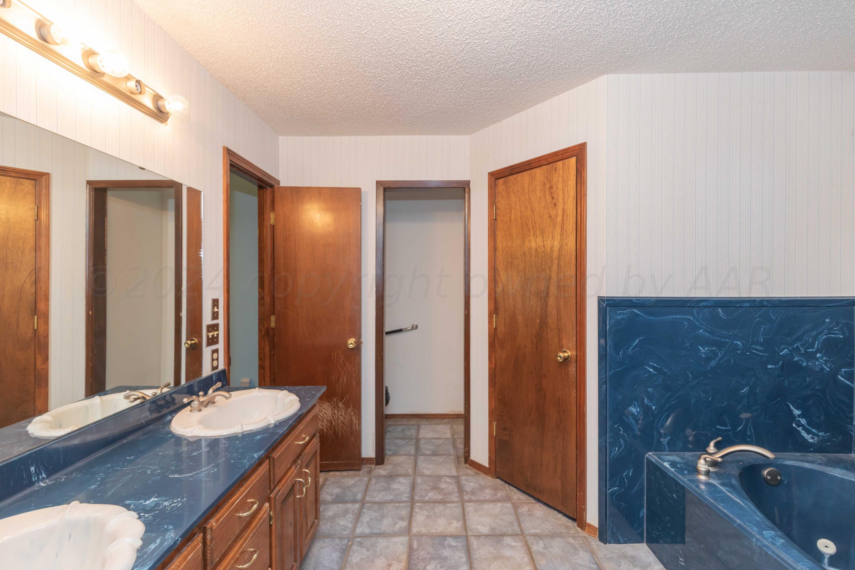 4721 Shawnee Trail Amarillo, TX 79109 - Photo 36 of 52 a bathroom with a granite countertop sink a mirror and a bathtub