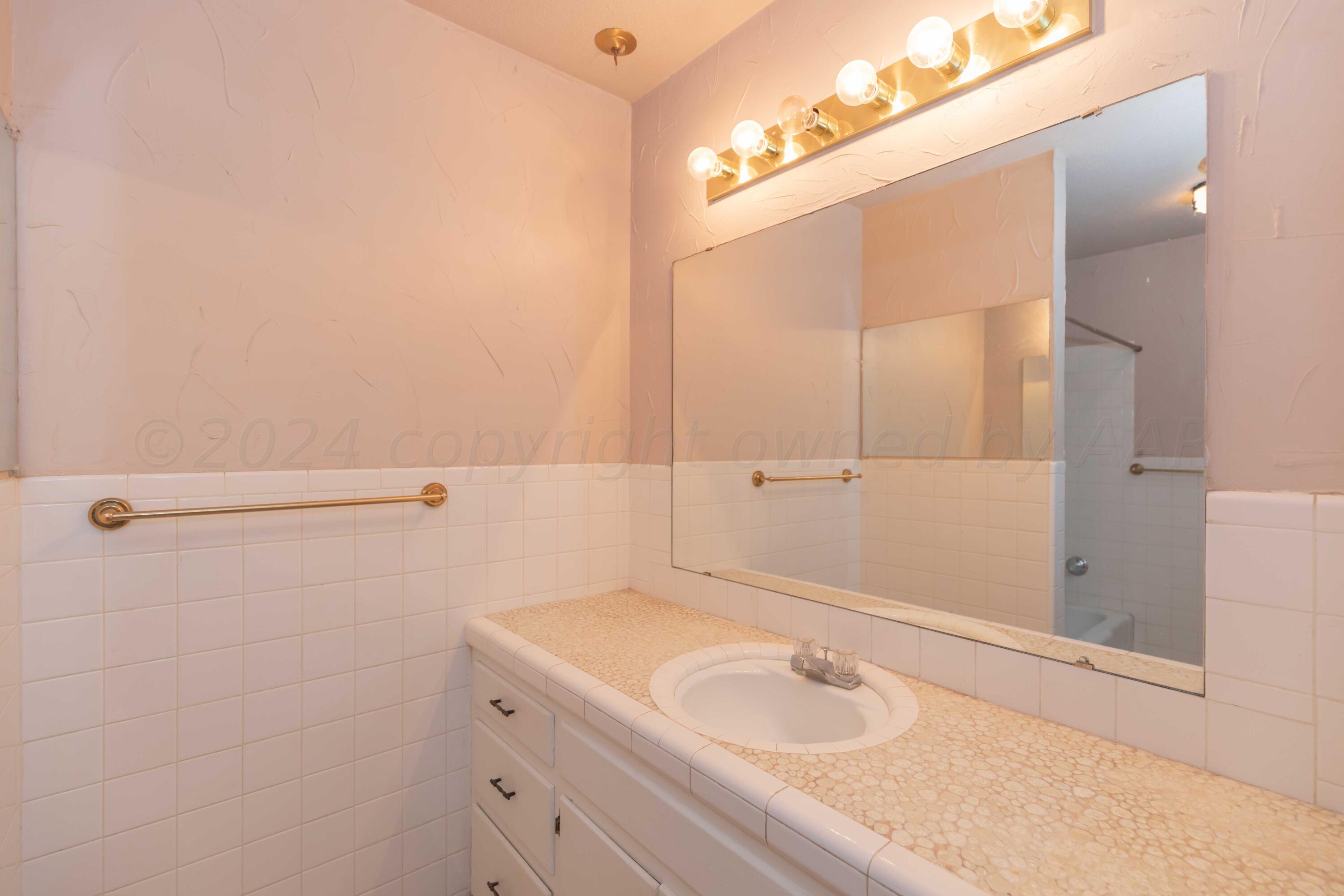 4721 Shawnee Trail Amarillo, TX 79109 - Photo 40 of 52 a bathroom with a granite countertop sink and a mirror