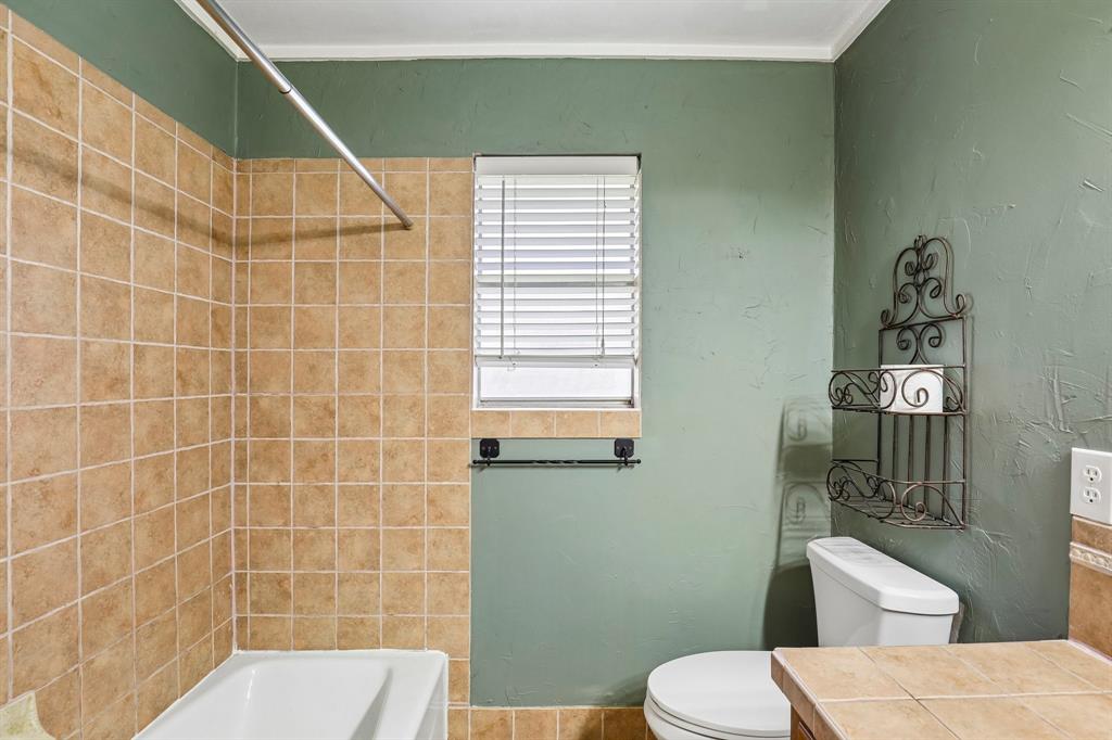 1600 South Timber Court Benbrook, TX 76126 - Photo 18 of 30 Bathroom featuring a white tub, shower with tan square tiles, white window blinds, and a toilet