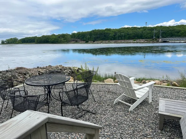a view of a lake with a table and chairs next to a yard