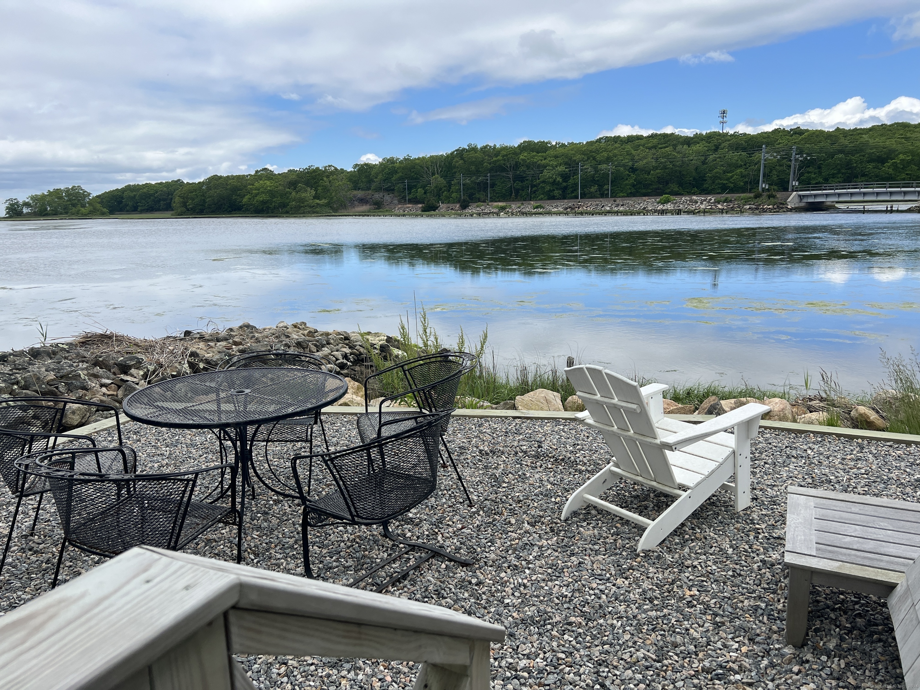 61 Old Black Point Road East Lyme, CT 06357 - Photo 12 of 27 a view of a lake with a table and chairs next to a yard