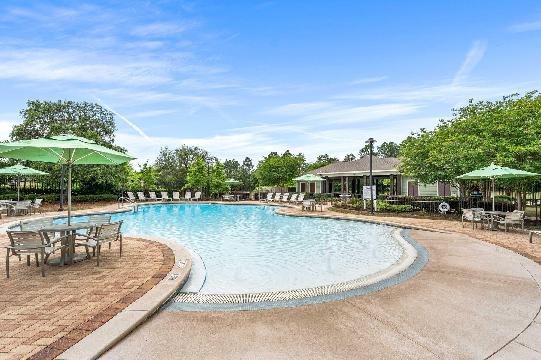656 Teal Street Crestview, FL 32539 - Photo 13 of 58 a view of a swimming pool with lawn chairs under an umbrella