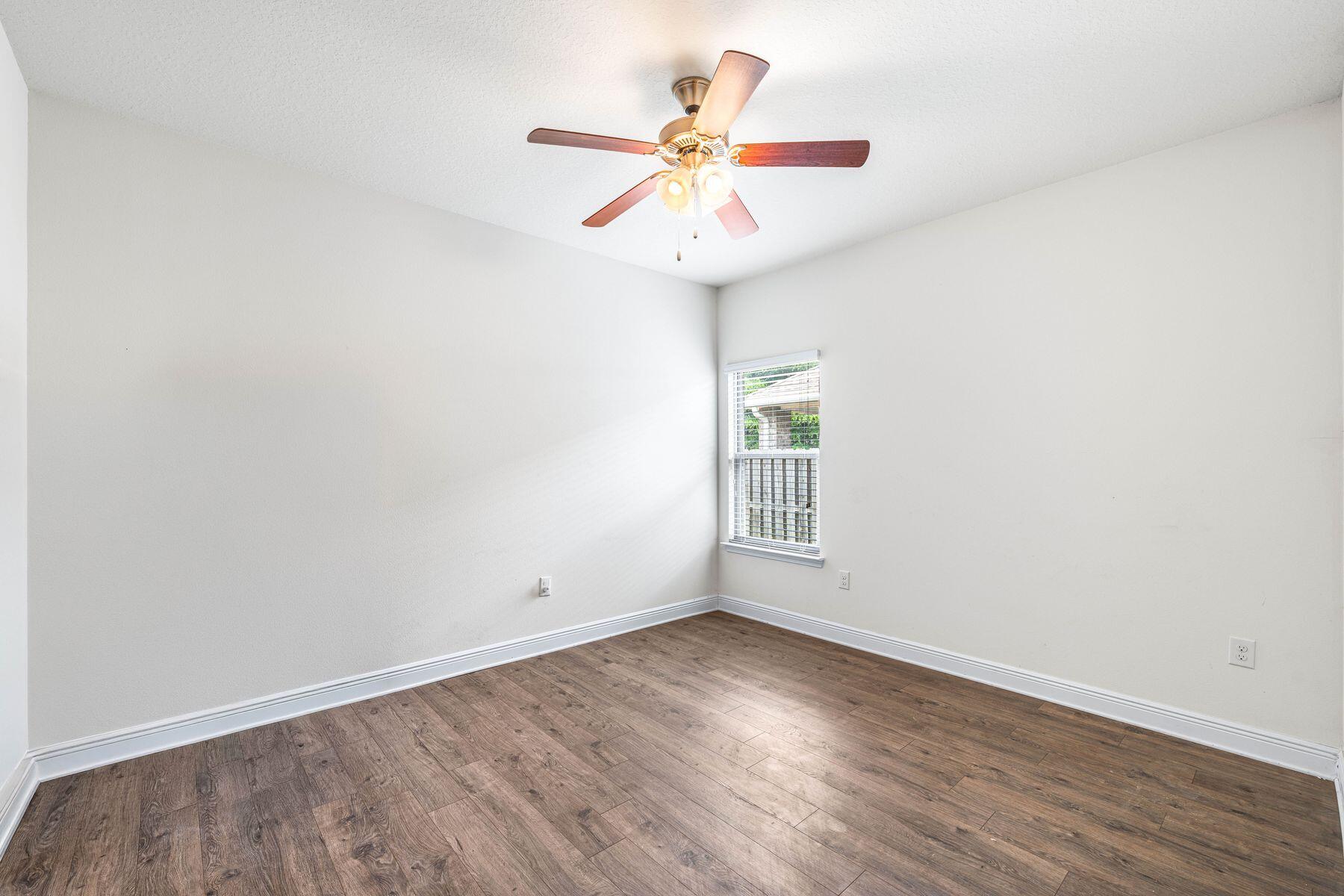 656 Teal Street Crestview, FL 32539 - Photo 35 of 58 an empty room with wooden floor fan and windows