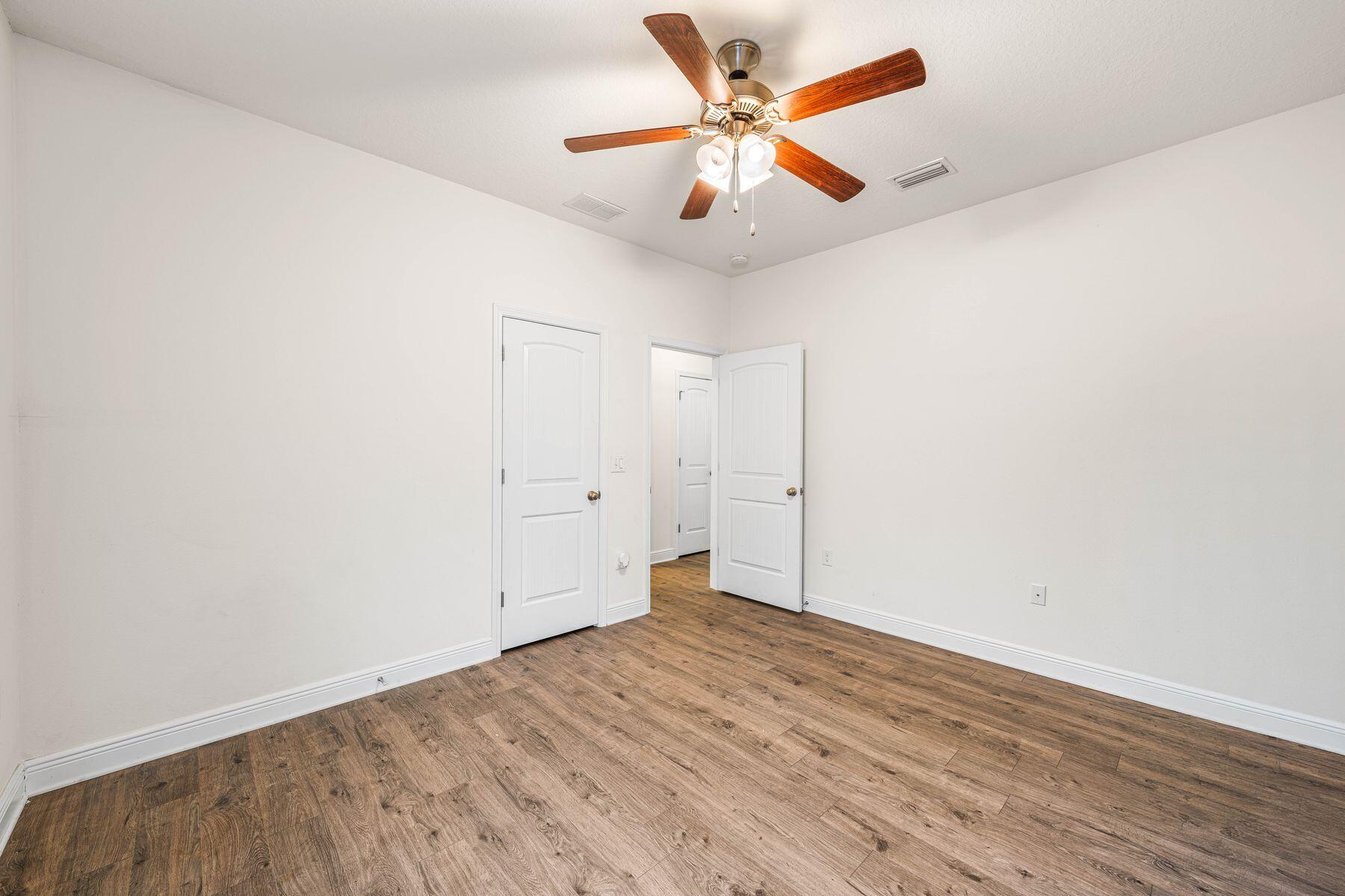 656 Teal Street Crestview, FL 32539 - Photo 36 of 58 an empty room with wooden floor and a ceiling fan
