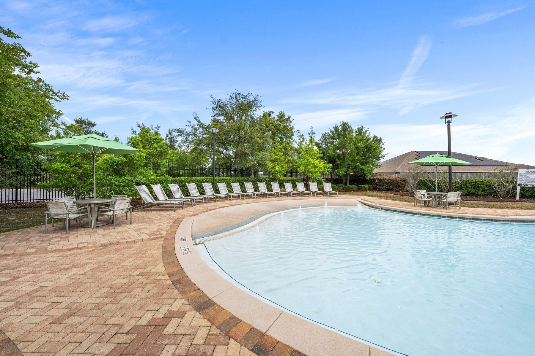 656 Teal Street Crestview, FL 32539 - Photo 45 of 58 a view of a swimming pool with lawn chairs under an umbrella