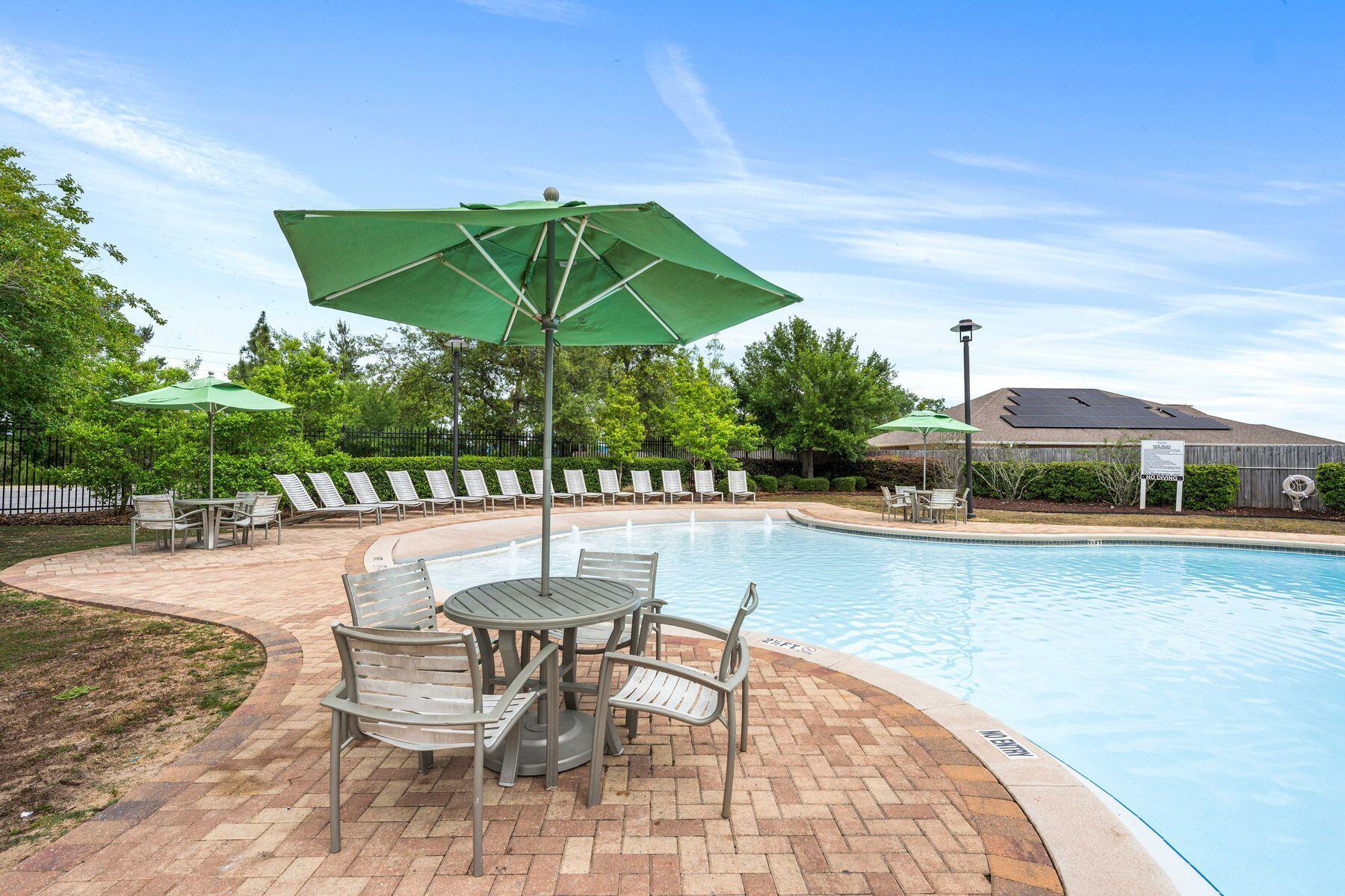 656 Teal Street Crestview, FL 32539 - Photo 46 of 58 a view of a swimming pool with a table and chairs under an umbrella