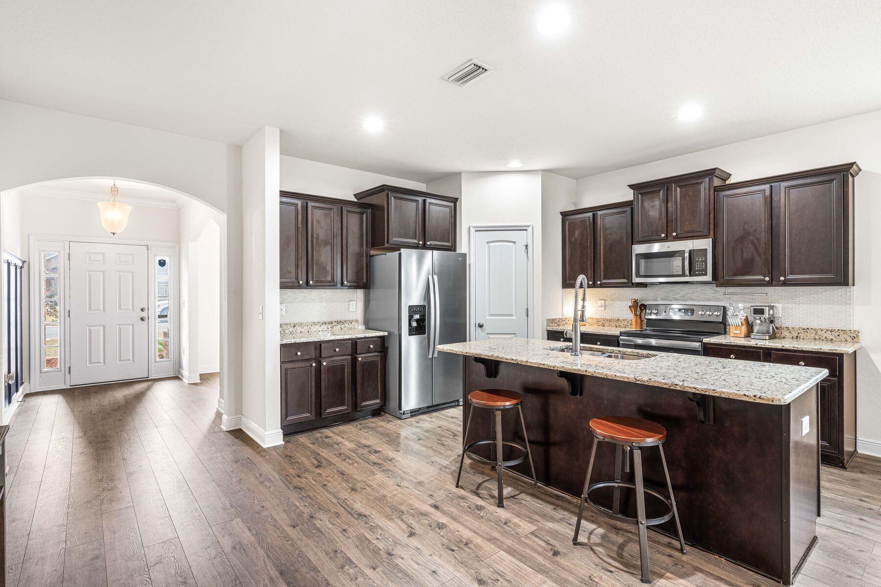 656 Teal Street Crestview, FL 32539 - Photo 5 of 58 a kitchen with stainless steel appliances a microwave a stove a sink dishwasher a refrigerator and cabinets with wooden floor