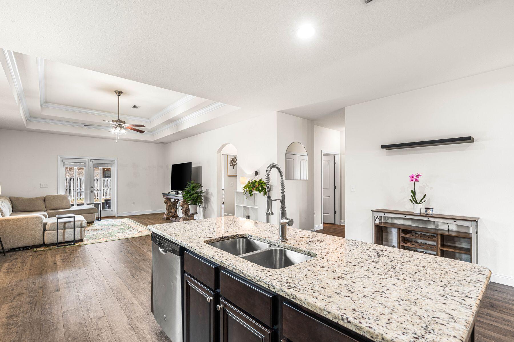 656 Teal Street Crestview, FL 32539 - Photo 6 of 58 a kitchen with granite countertop a sink dishwasher and a stove with wooden floor