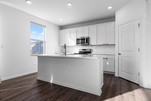 a kitchen with kitchen island white cabinets a sink and dishwasher with wooden floor