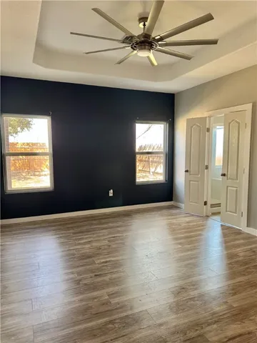 a view of an empty room with a window and wooden floor