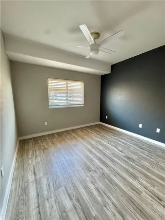 an empty room with wooden floor fan and windows