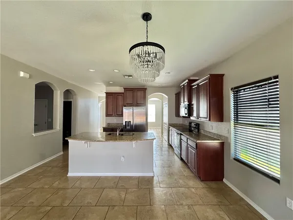 a large kitchen with stainless steel appliances granite countertop a sink dishwasher a microwave oven and a dining table with wooden cabinet