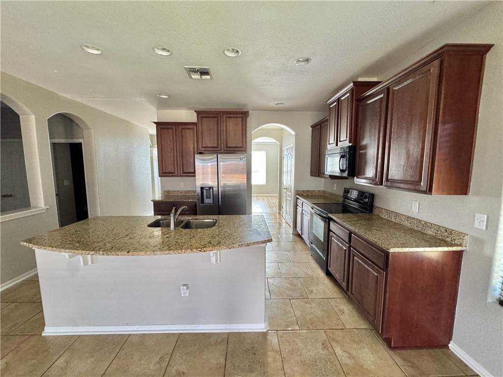 322 Pacific Drive Portland, TX 78374 - Photo 7 of 22 a large kitchen with kitchen island granite countertop a sink refrigerator and cabinets
