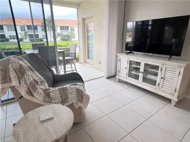 a living room with furniture a flat screen tv and floor to ceiling windows