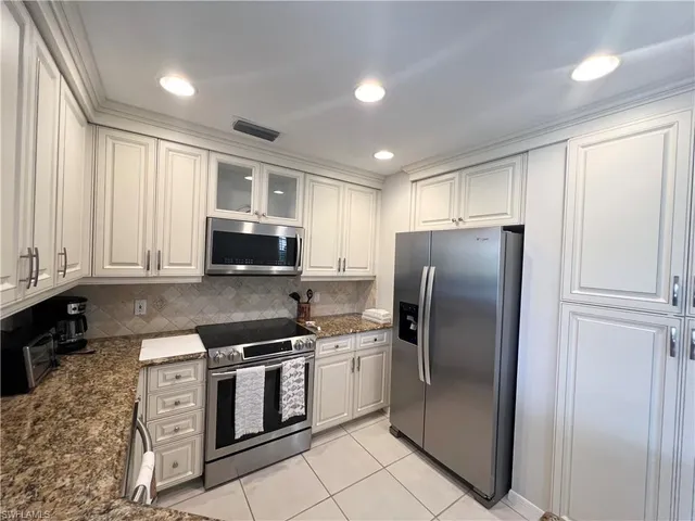 a kitchen with stainless steel appliances granite countertop a refrigerator sink and stove