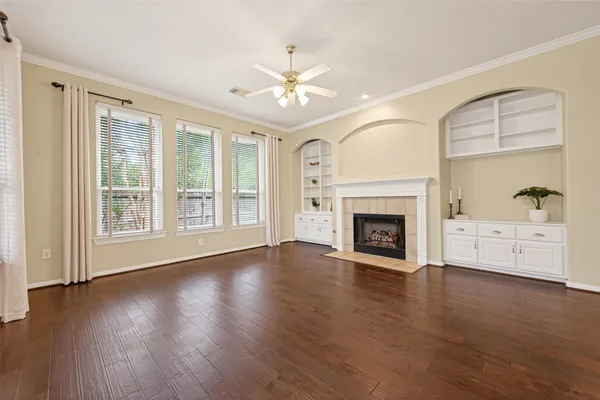 a view of an empty room with wooden floor fireplace and a window