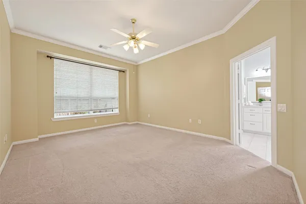 an empty room with chandelier fan and windows