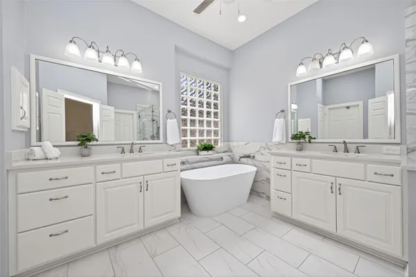 a spacious bathroom with a double vanity sink mirror and bathtub