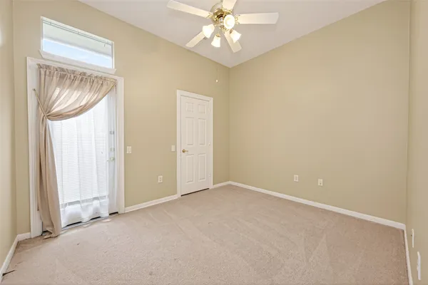 an empty room with a chandelier fan and a window