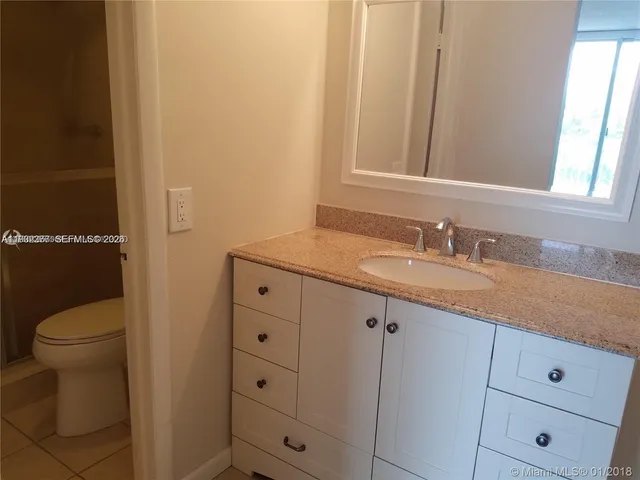 a bathroom with a granite countertop toilet sink and mirror