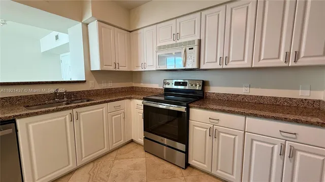 a kitchen with granite countertop white cabinets and stainless steel appliances