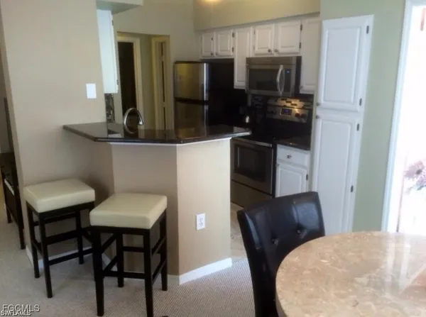 a bathroom with a sink a refrigerator and chairs