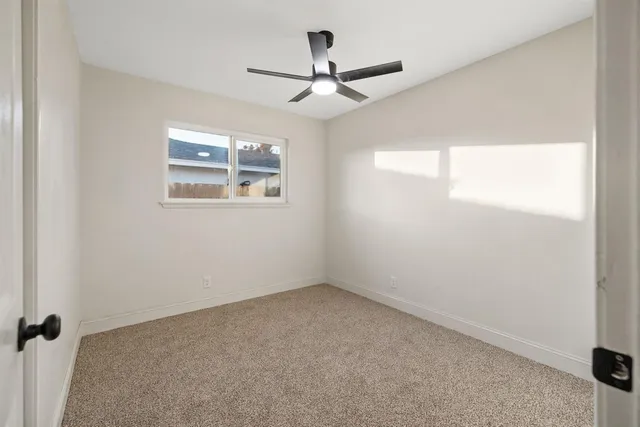 an empty room with a window and a fan