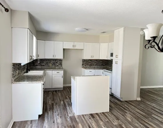 a kitchen with a refrigerator a stove and white cabinets with wooden floor