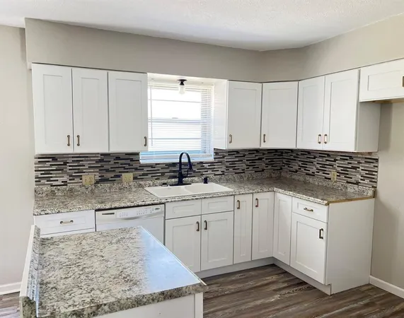 a kitchen with granite countertop white cabinets and sink