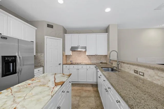 a large kitchen with granite countertop a sink stove refrigerator and cabinets