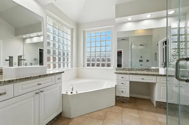 a spacious bathroom with a granite countertop tub sink shower and mirror