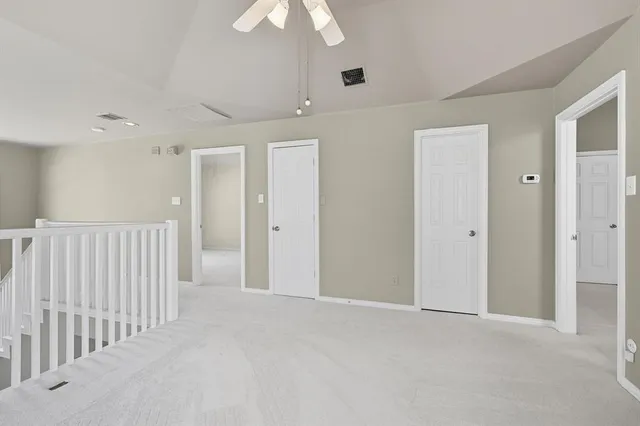 a view of an empty room and chandelier fan