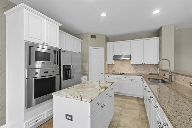 a kitchen with stainless steel appliances granite countertop a sink stove and refrigerator