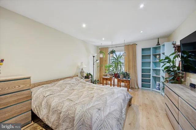 a bed sitting in a spacious bedroom next to a window and a flat screen tv