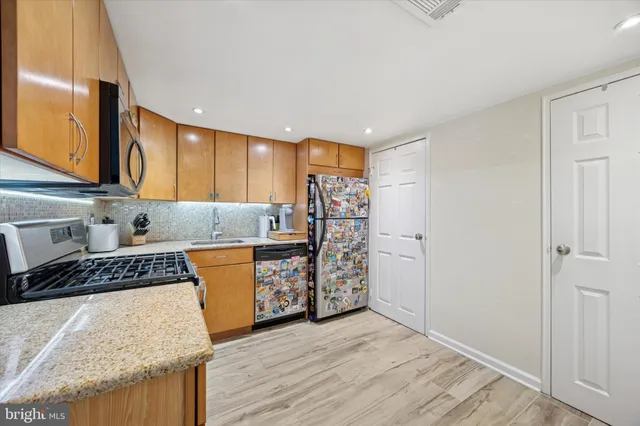 a kitchen with stainless steel appliances granite countertop a stove a sink and a refrigerator