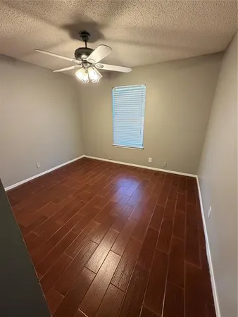en empty room with wooden floor and fan