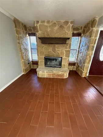 a view of an empty room with wooden floor fireplace and a window