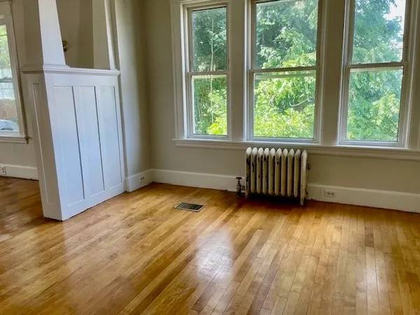 a view of an empty room with wooden floor and a window