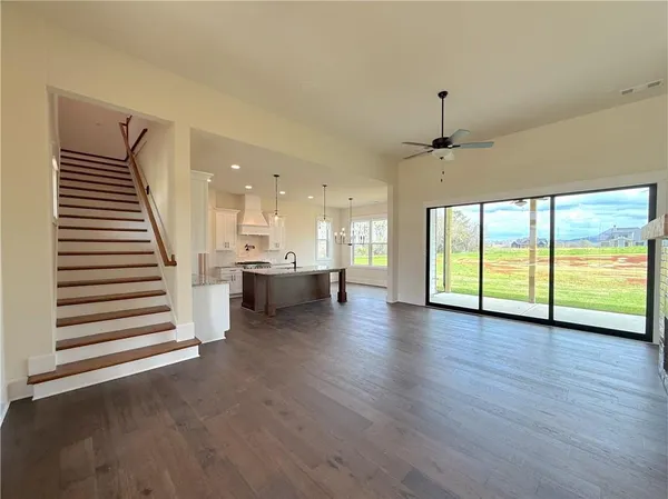 a view of a livingroom with wooden floor a ceiling fan and windows