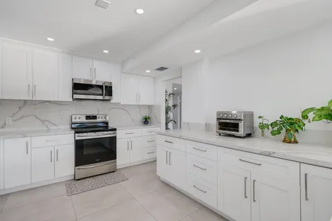 a kitchen with white cabinets and appliances