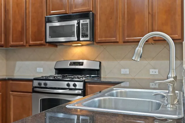 a kitchen with granite countertop a stove top oven microwave and cabinets