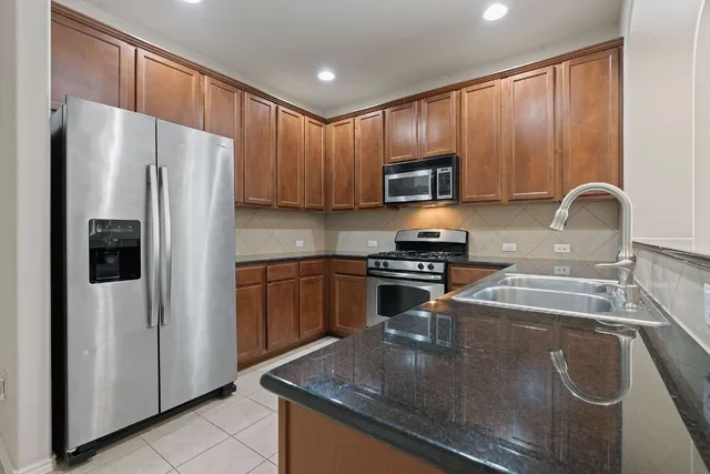 a kitchen with stainless steel appliances granite countertop a refrigerator stove a sink and a microwave