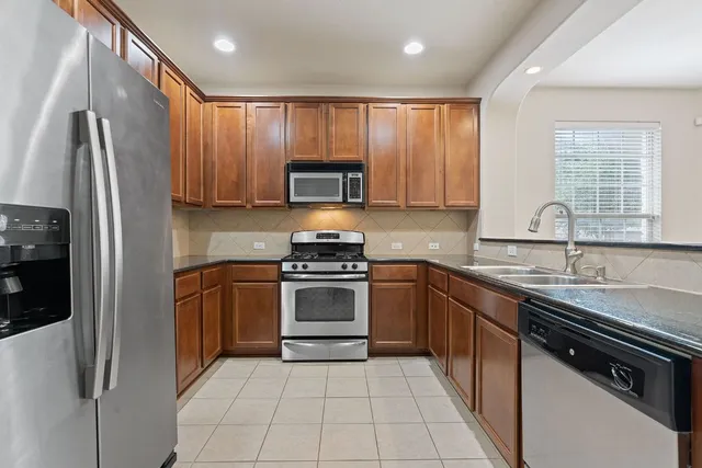 a kitchen with stainless steel appliances granite countertop a refrigerator sink and stove
