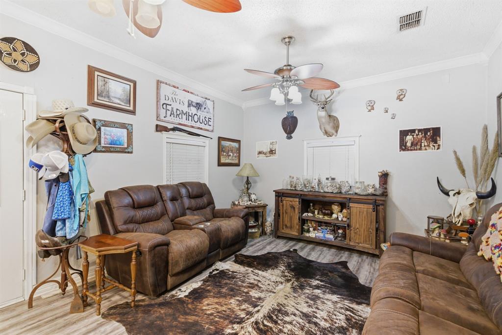 302 Tower Road Rio Vista, TX 76093 - Photo 17 of 29 Living area featuring wood-finish flooring, a ceiling fan with light fixture, and crown molding