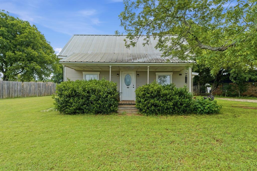 302 Tower Road Rio Vista, TX 76093 - Photo 2 of 29 Single-story residence featuring a metal roof, a covered front porch, and mature landscaping