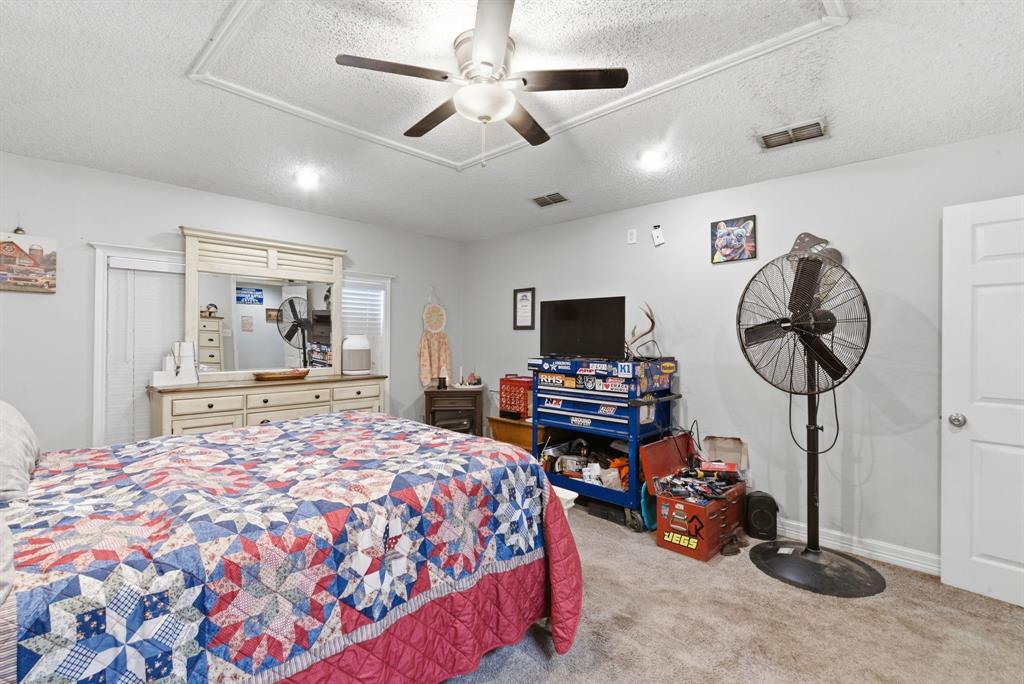 302 Tower Road Rio Vista, TX 76093 - Photo 25 of 29 Carpeted bedroom featuring a tray ceiling, ceiling fan with light fixture, and light gray wall paint