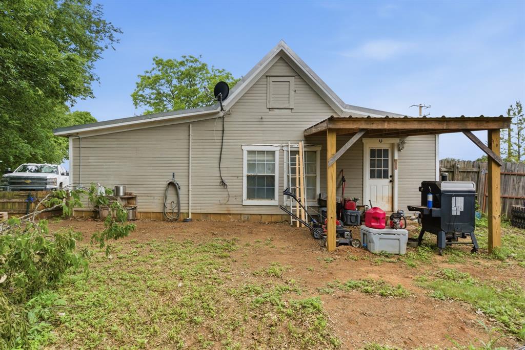 302 Tower Road Rio Vista, TX 76093 - Photo 28 of 29 Rear exterior with light-colored siding, a covered patio area, and a white entry door